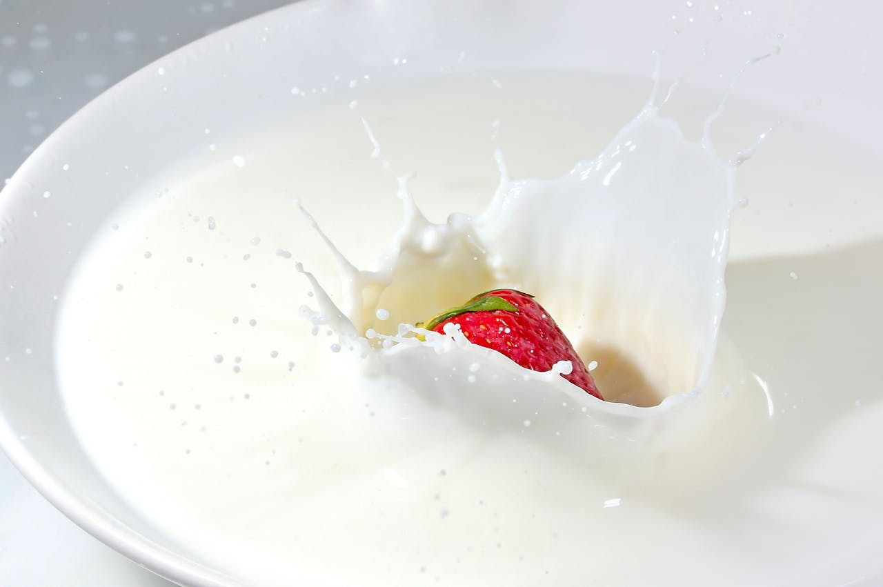 hero-img-01 Detailed image of a strawberry splashing into fresh milk, creating a high-impact splash effect.